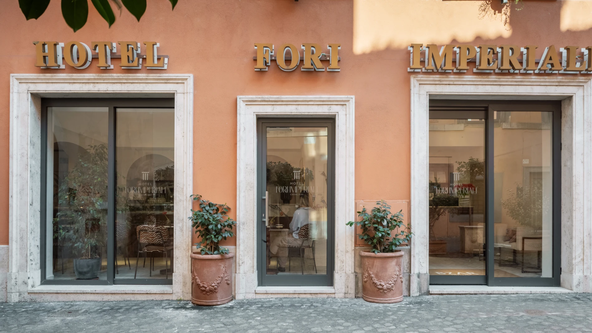 Facciata elegante, vetrine su strada e insegna su edificio storico nel centro di Roma, zona Fori Imperiali - Hotel Fori Imperiali, BZAR hotels a Roma